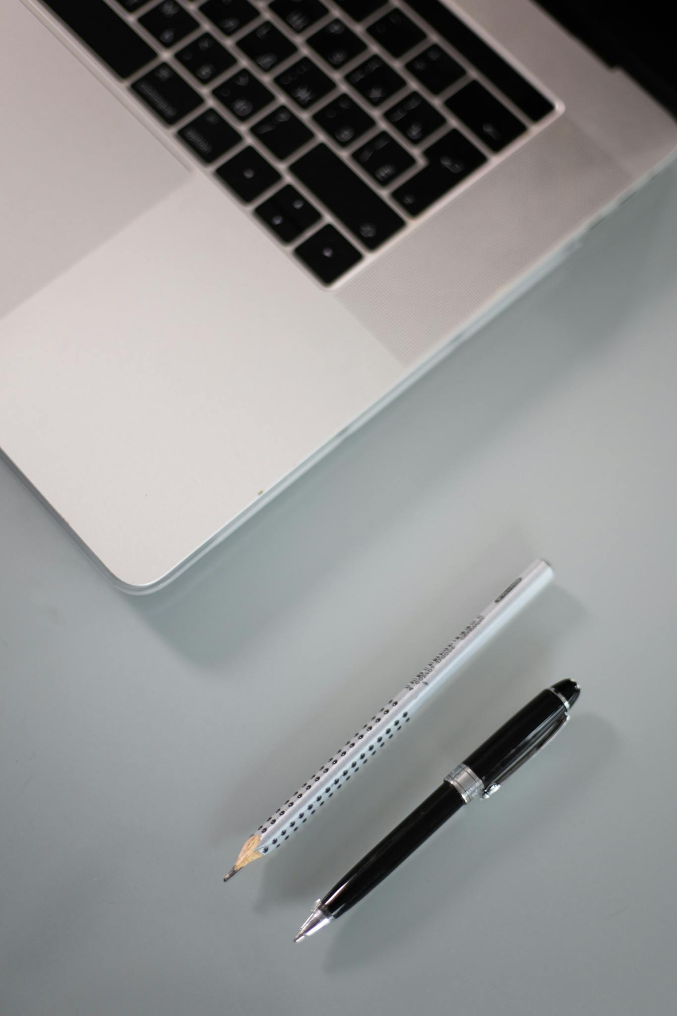 Minimalist workspace setup with a sleek laptop, pen, and pencil on a modern desk.